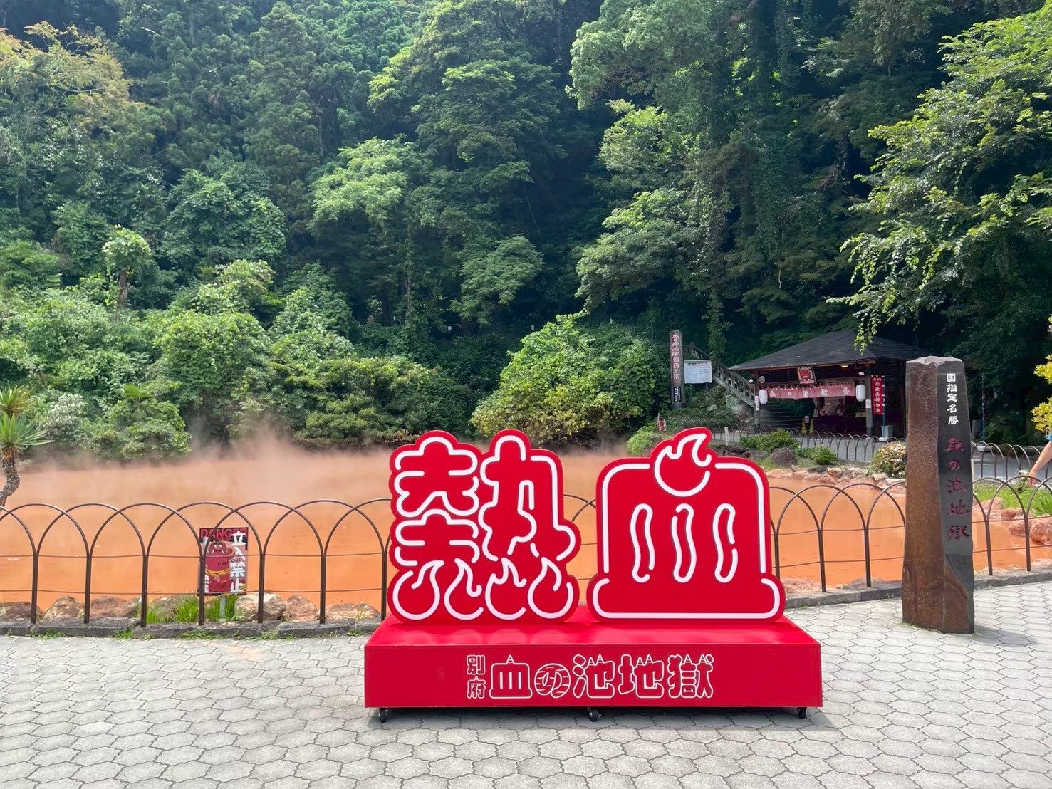 Escultura roja con el kanji de «sangre caliente» frente a la poza