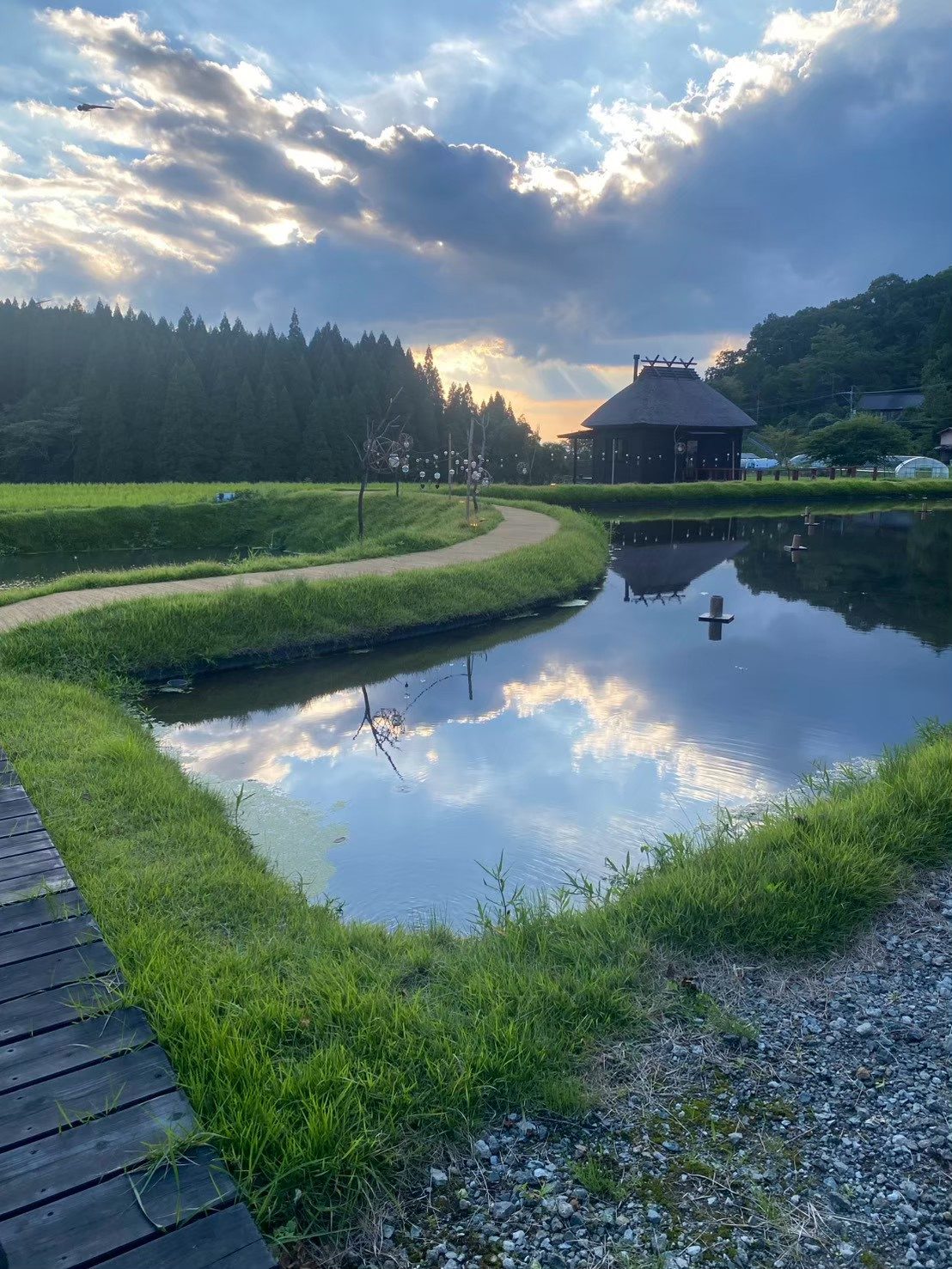 Estanque al atardecer y casa con techo de paja en Kurokawa
